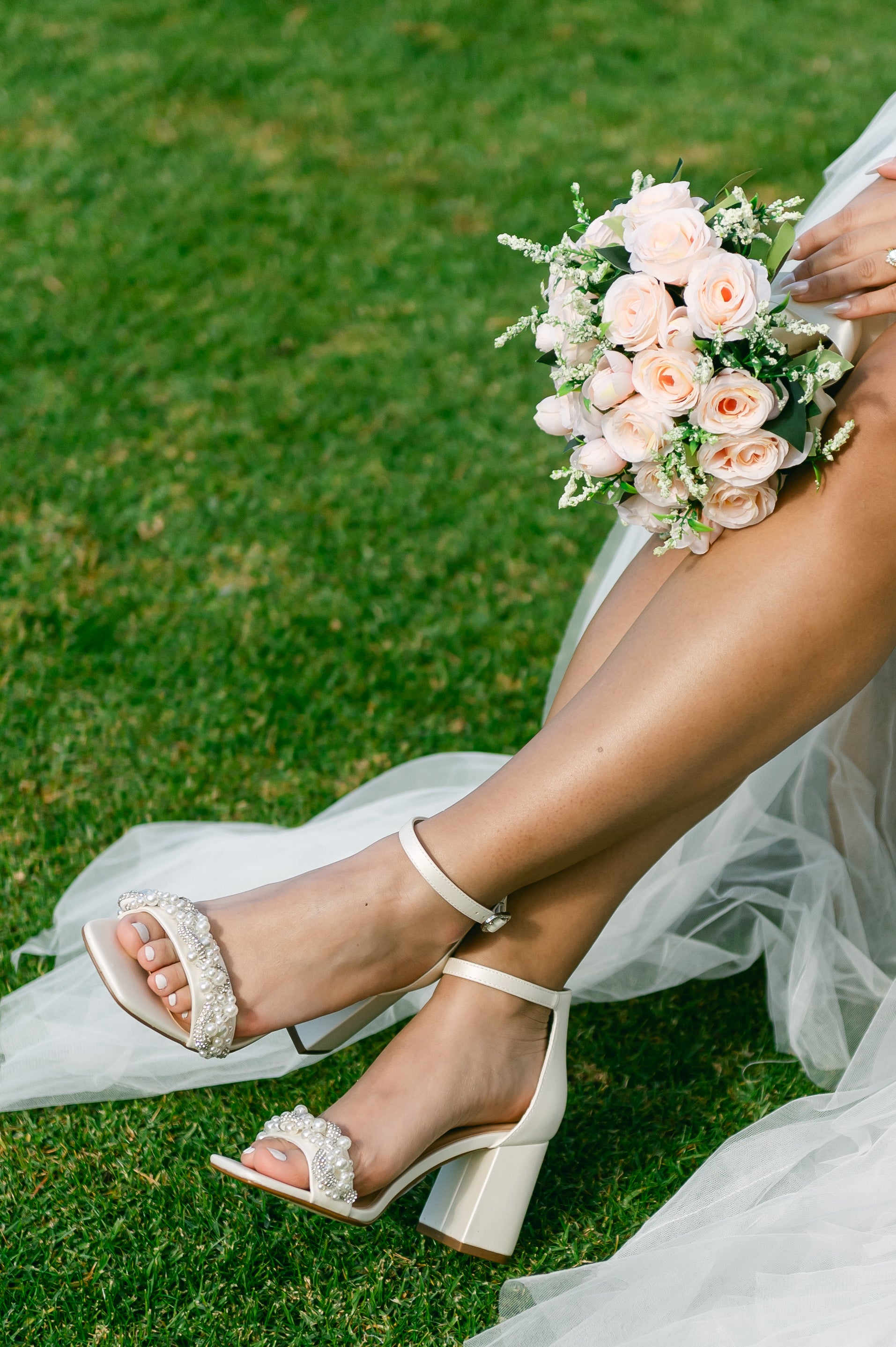 Pearls and rhinestones intertwined on a white single-band 3.25" ankle strap block heel worn by a woman in a white dress