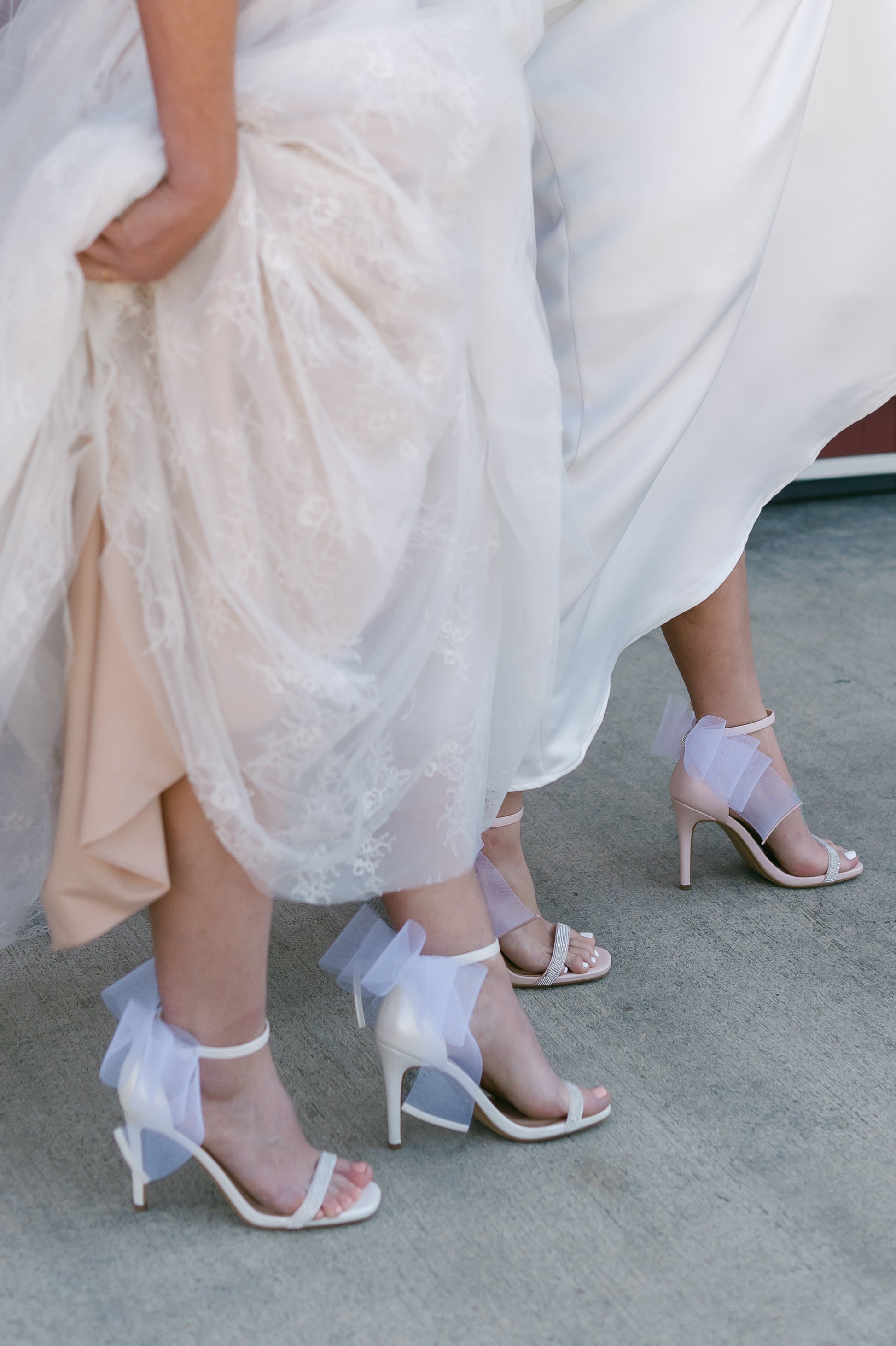 4" stiletto heels in pink and white with rhinestone band and wire mesh statement bow worn by two women in white dresses