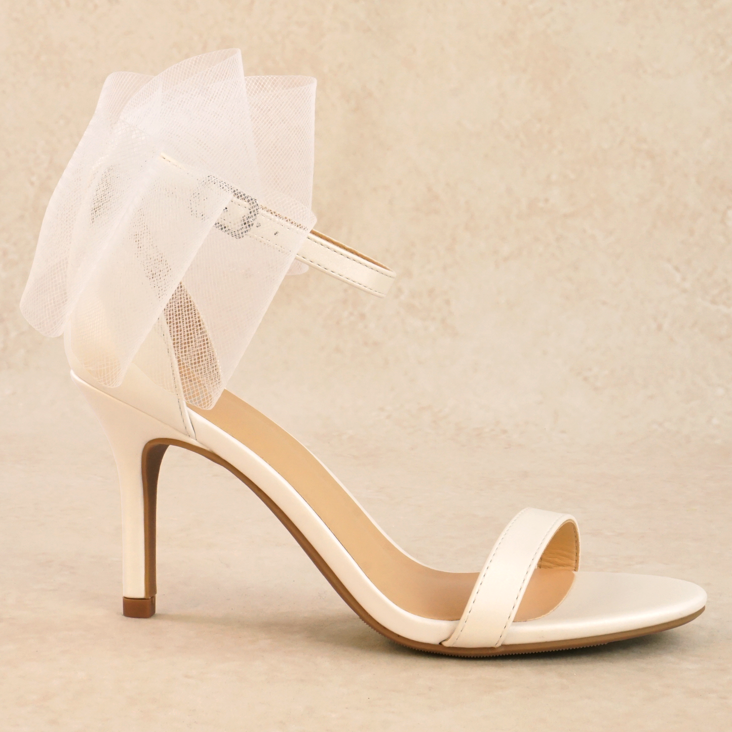 A stiletto heeled sandal with an adjustable ankle strap and mesh bow detail on the back