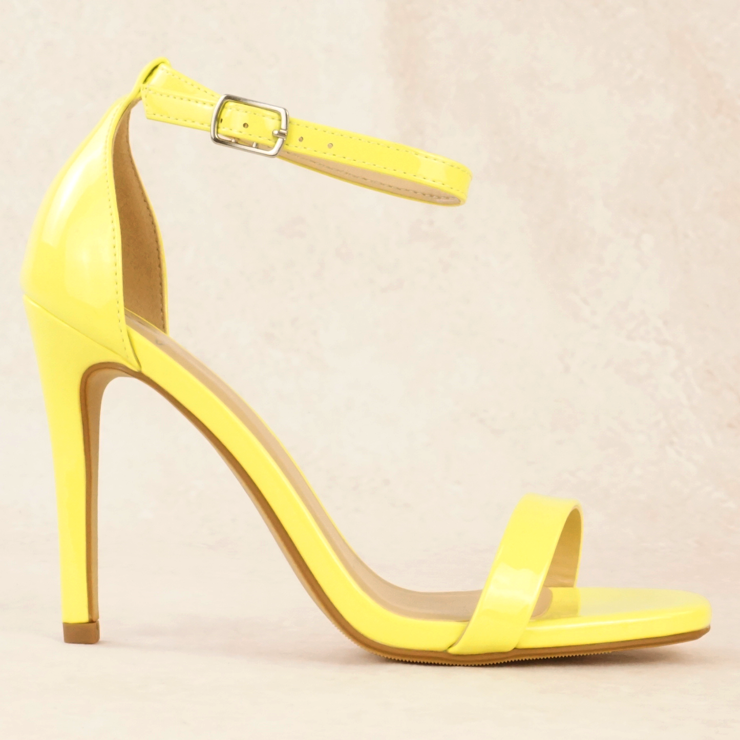 A yellow patent material stiletto heel with adjustable ankle strap